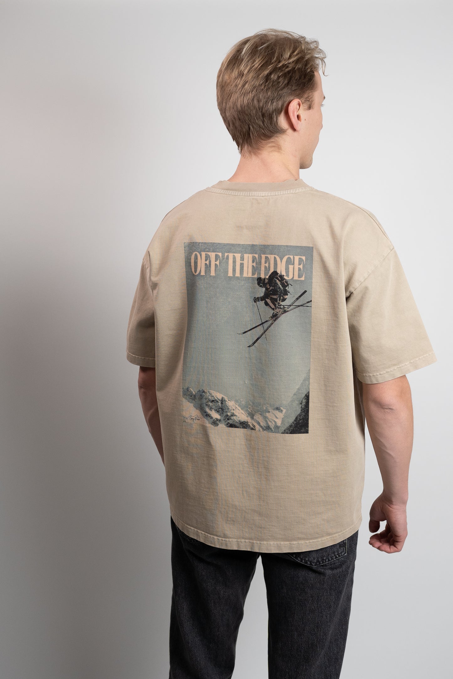 baksiden av en brun t skjorte med bilde av en på ski på ryggen