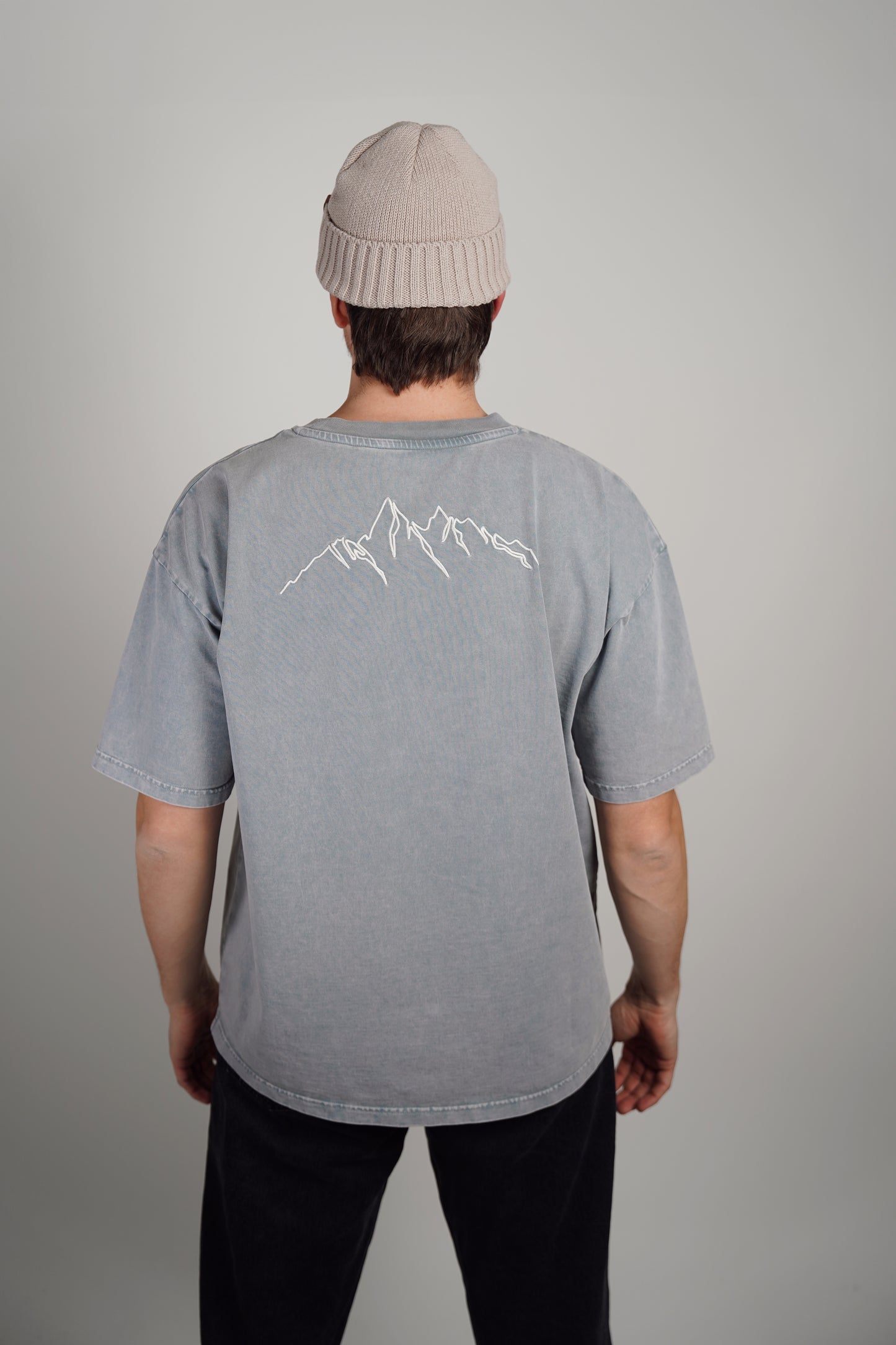 baksiden av en blå t skjorte med hvite streker på ryggen som illustrerer fjell