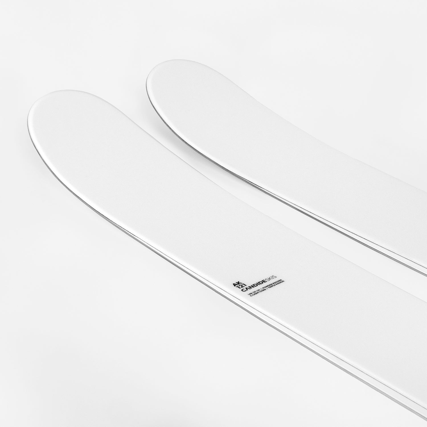 tuppen av noen hvite ski med liten svart skrift, på hvit bakgrunn.