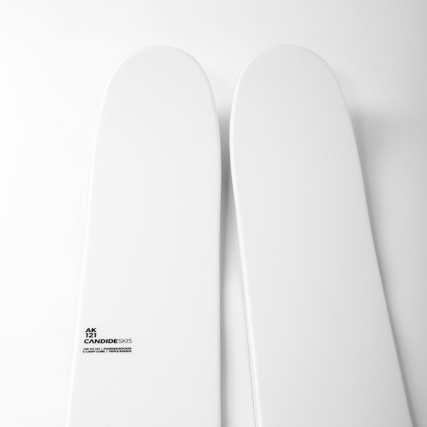 tuppen av noen hvite ski med liten sort skrift, på hvit bakgrunn