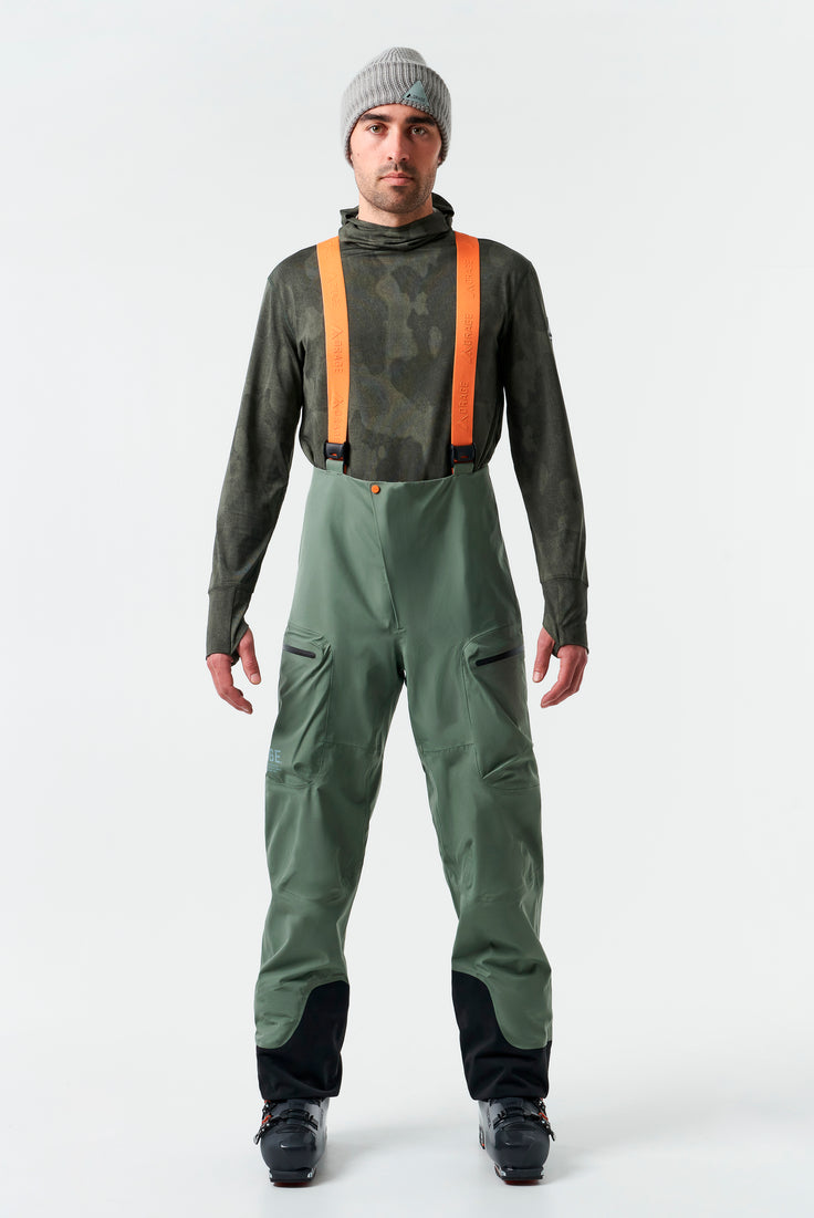 fremsiden av en grønn ski bukse med oransje stropper